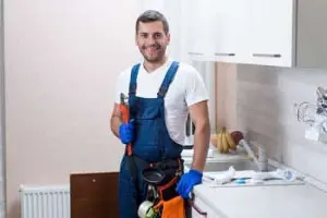 Calgary plumber installing a garburator under kitchen sink