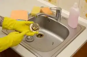 Plumber clearing clogged bathroom drain in Okotoks