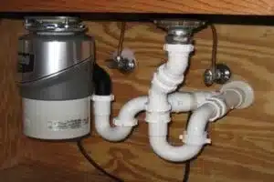 Plumber repairing garburator system in Calgary home