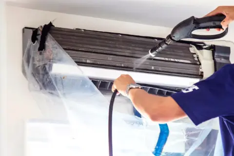 Technician cleaning AC condenser coils in Calgary