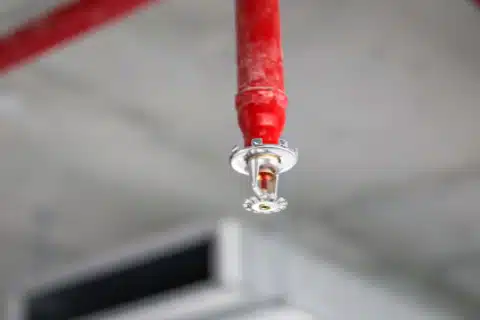 Technician installing sprinkler piping overhead